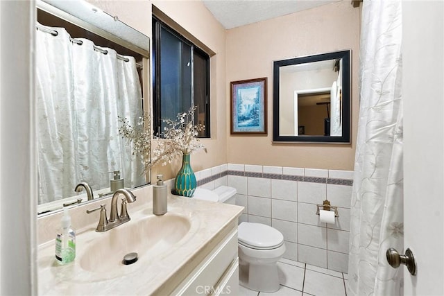 bathroom with toilet, vanity, tile walls, and tile patterned flooring