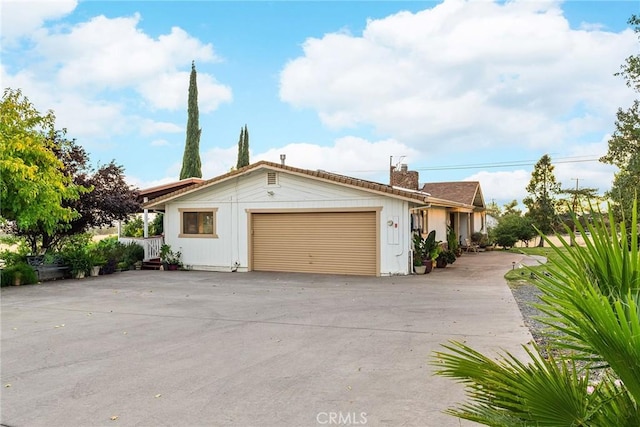 single story home with driveway, a chimney, and a garage