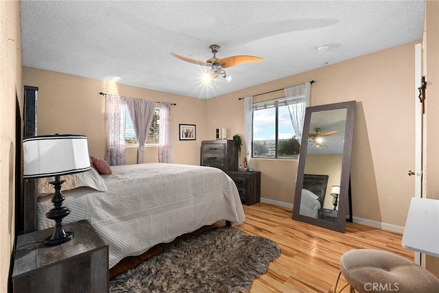 bedroom with baseboards, wood finished floors, ceiling fan, and a textured ceiling