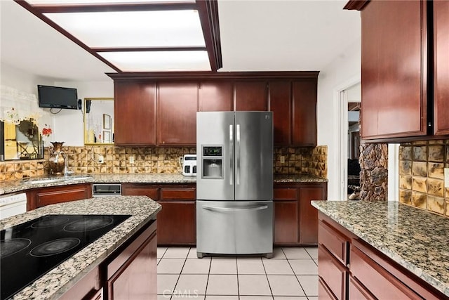 kitchen with a sink, backsplash, stainless steel fridge, black electric cooktop, and light tile patterned floors