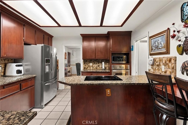 kitchen featuring light stone countertops, light tile patterned floors, backsplash, and appliances with stainless steel finishes