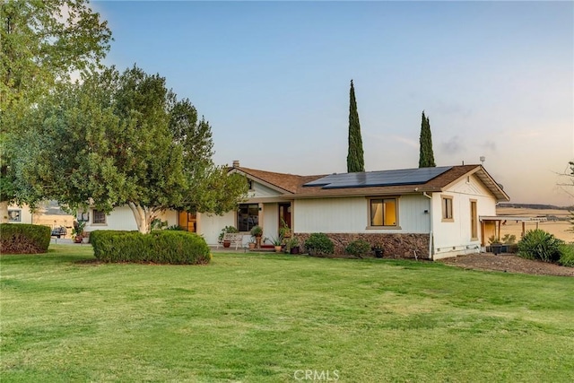 ranch-style home featuring a lawn and solar panels