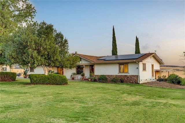 single story home with roof mounted solar panels and a front yard