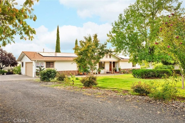 ranch-style house featuring a garage, a front lawn, and solar panels