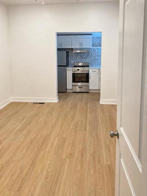 interior space featuring stainless steel appliances, tasteful backsplash, white cabinetry, and light hardwood / wood-style flooring