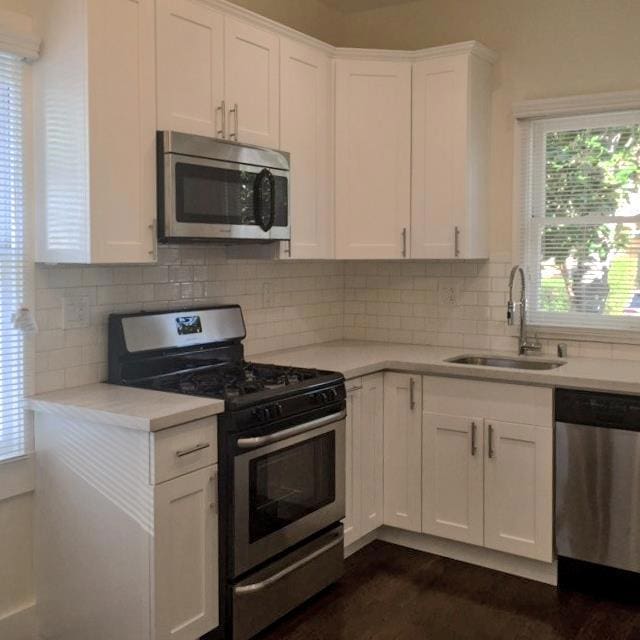 kitchen featuring stainless steel appliances, tasteful backsplash, sink, and white cabinets