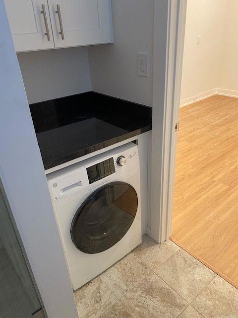 clothes washing area featuring washer / clothes dryer and light hardwood / wood-style flooring