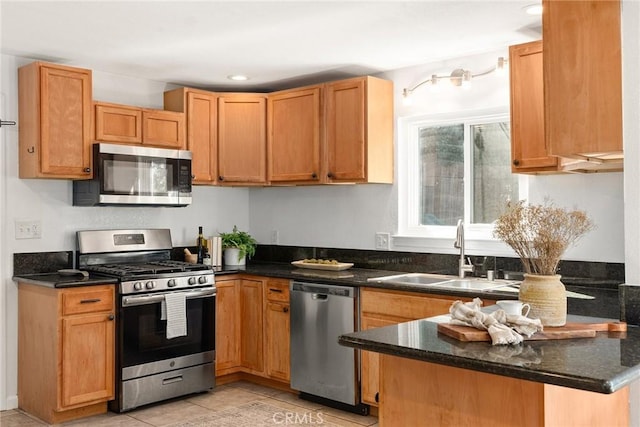 kitchen featuring stainless steel appliances, dark stone counters, sink, kitchen peninsula, and light tile patterned flooring