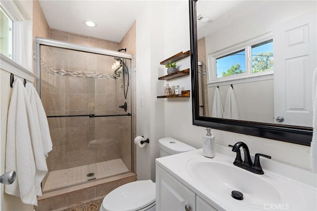 bathroom featuring toilet, a shower with door, and vanity