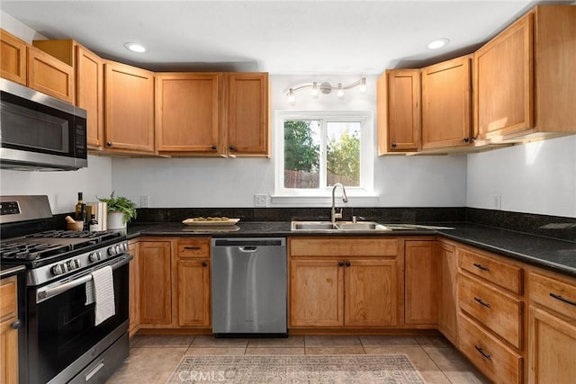 kitchen with light tile patterned floors, appliances with stainless steel finishes, sink, and dark stone counters