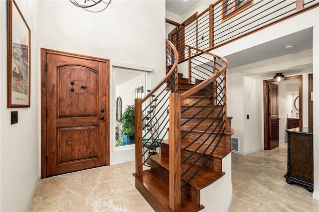 foyer featuring visible vents, stairway, a towering ceiling, and baseboards