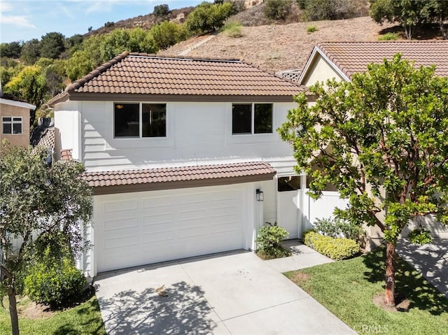 mediterranean / spanish-style house featuring a garage, driveway, and a tile roof