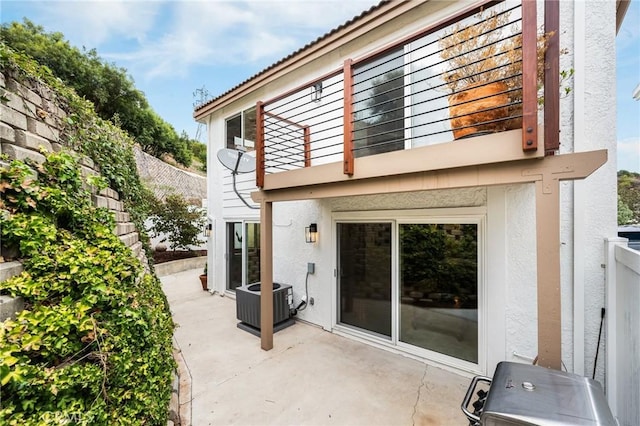 rear view of house featuring a patio, a balcony, fence, cooling unit, and stucco siding