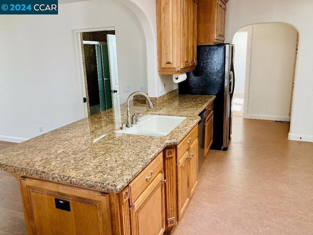 kitchen featuring kitchen peninsula, stainless steel appliances, light stone counters, and sink