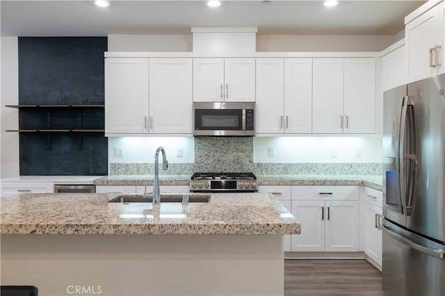 kitchen with light stone countertops, appliances with stainless steel finishes, sink, and white cabinetry