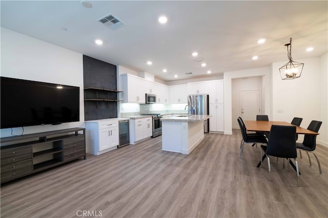 kitchen with hanging light fixtures, light hardwood / wood-style floors, white cabinetry, stainless steel appliances, and a center island