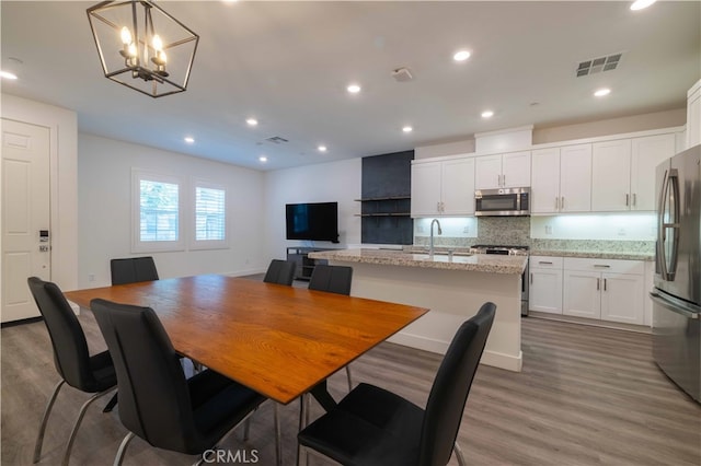 dining space with an inviting chandelier, sink, and hardwood / wood-style floors