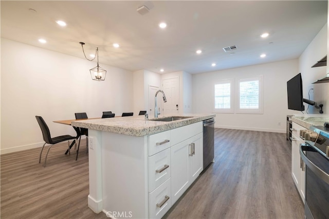 kitchen with white cabinets, sink, a center island with sink, dark wood-type flooring, and stainless steel appliances