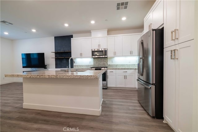 kitchen with white cabinets, a center island with sink, appliances with stainless steel finishes, and dark hardwood / wood-style flooring