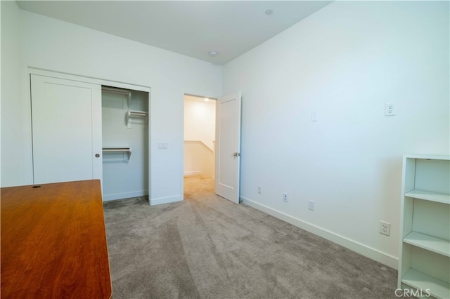 unfurnished bedroom with light colored carpet and a closet