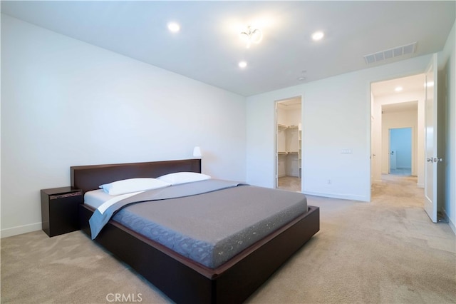 bedroom featuring a spacious closet, a closet, and light colored carpet