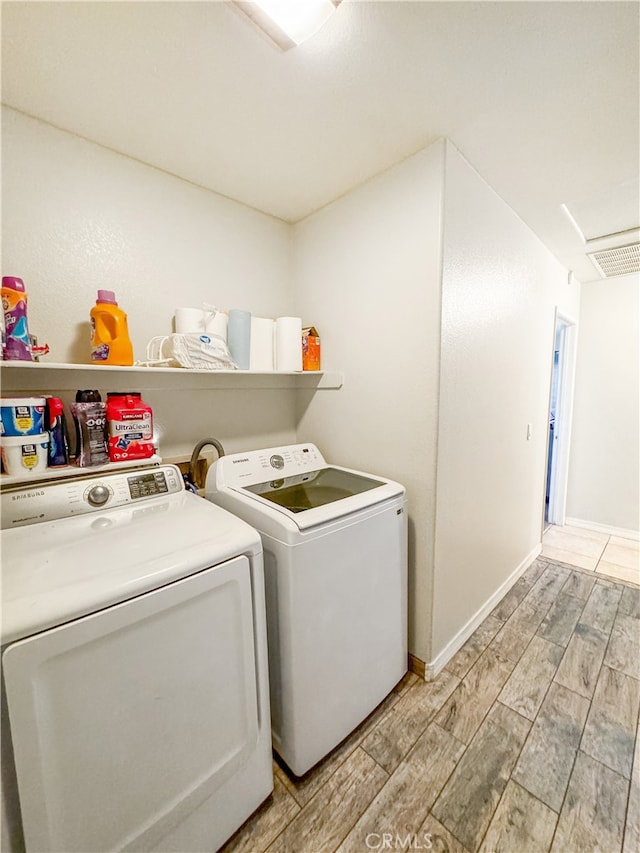 laundry room featuring separate washer and dryer and light hardwood / wood-style flooring