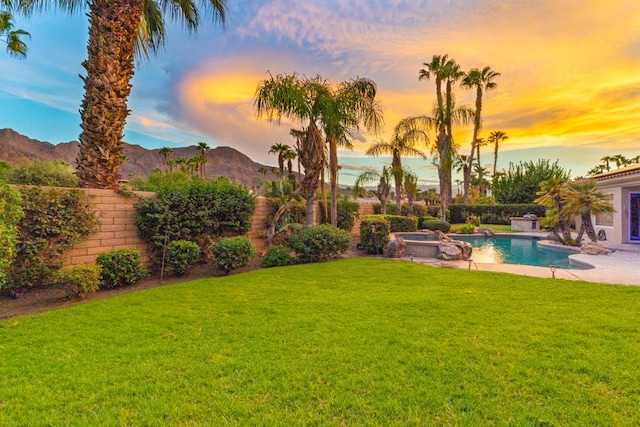 yard at dusk featuring a pool with hot tub, a mountain view, and a patio area