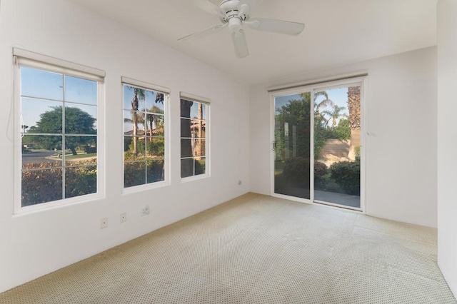 carpeted spare room with ceiling fan and plenty of natural light