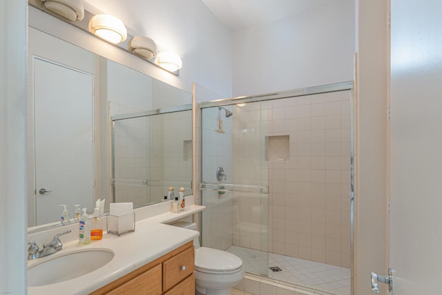 bathroom featuring a shower with shower door, vanity, and toilet