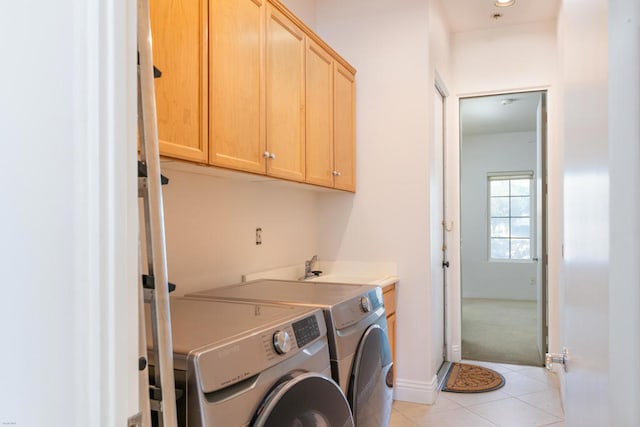 clothes washing area with cabinets, independent washer and dryer, and light tile patterned floors