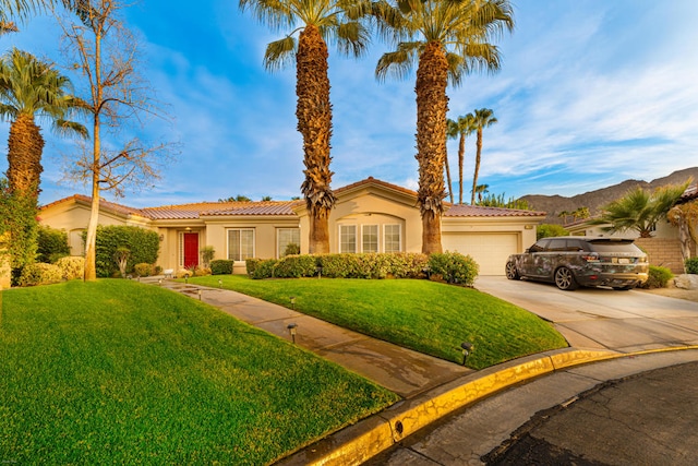 view of front of home with a mountain view, a garage, and a front lawn