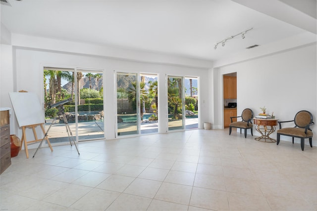 living area with rail lighting and light tile patterned floors