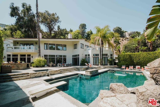 view of swimming pool with a diving board, an in ground hot tub, and a patio area