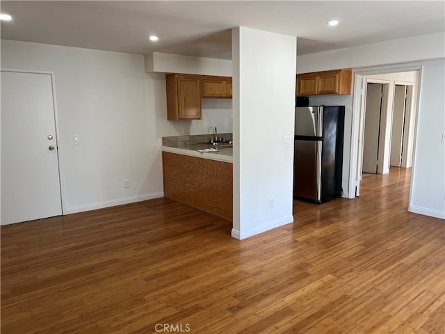 kitchen featuring stainless steel fridge, sink, and wood-type flooring