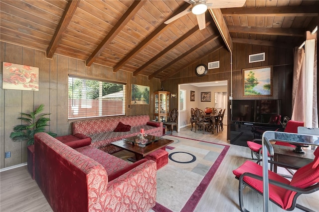 living room featuring vaulted ceiling with beams, light hardwood / wood-style floors, wood walls, and ceiling fan