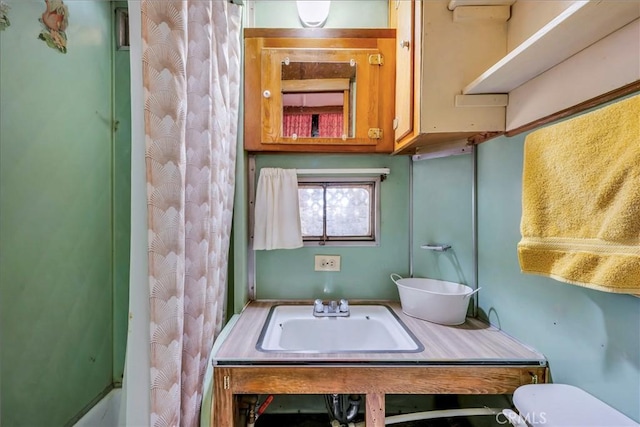 bathroom featuring curtained shower, toilet, and a sink