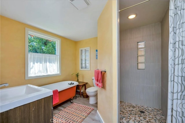 bathroom with visible vents, toilet, a freestanding bath, a tile shower, and a sink