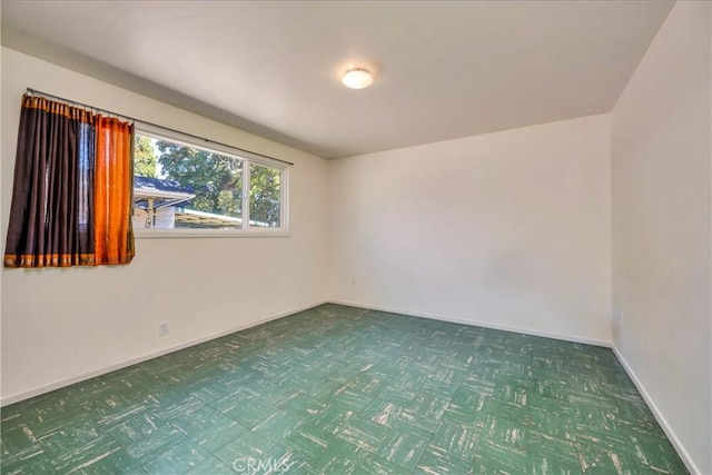 spare room with tile patterned floors and baseboards