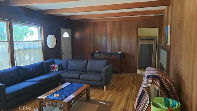 living area featuring beamed ceiling, wood walls, and wood finished floors