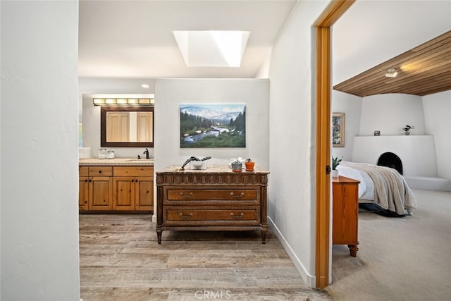 bathroom with vanity, a skylight, and hardwood / wood-style flooring