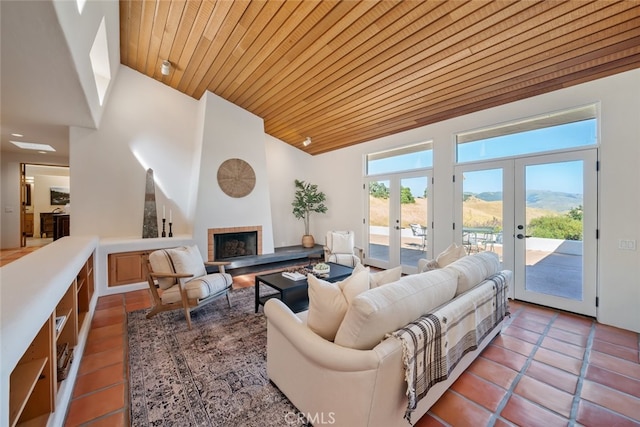 living room with wood ceiling, a mountain view, french doors, and a brick fireplace