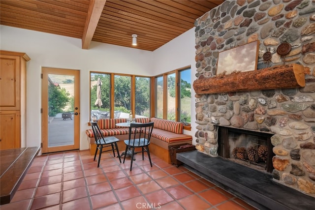 dining room featuring wood ceiling, plenty of natural light, tile patterned floors, and a stone fireplace