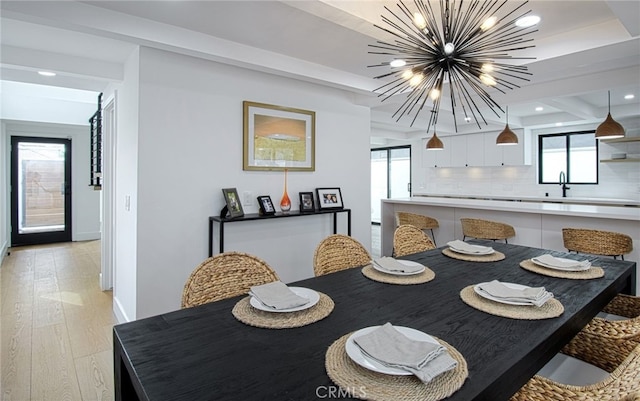 dining area featuring light hardwood / wood-style floors, a healthy amount of sunlight, sink, and a chandelier