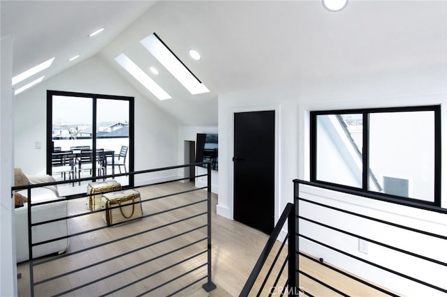 hall featuring light hardwood / wood-style floors and vaulted ceiling with skylight