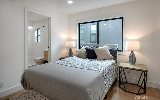 bedroom featuring multiple windows, ensuite bathroom, and hardwood / wood-style floors