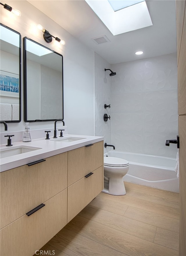 full bathroom featuring a skylight, tiled shower / bath combo, wood-type flooring, toilet, and vanity