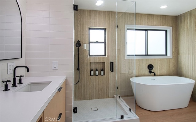 bathroom featuring plus walk in shower, hardwood / wood-style floors, vanity, and a healthy amount of sunlight