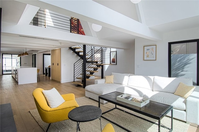 living room with hardwood / wood-style floors, high vaulted ceiling, beamed ceiling, and sink