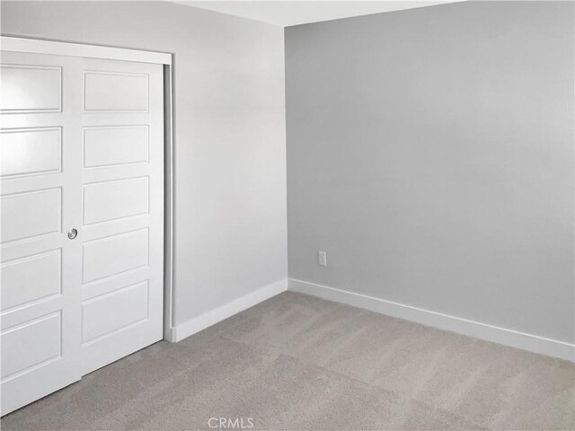 unfurnished bedroom with light colored carpet and a closet