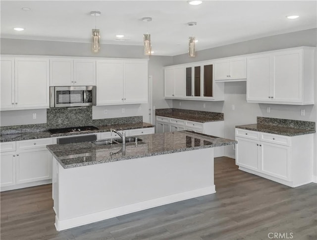 kitchen featuring dark hardwood / wood-style flooring, a center island with sink, white cabinets, and pendant lighting